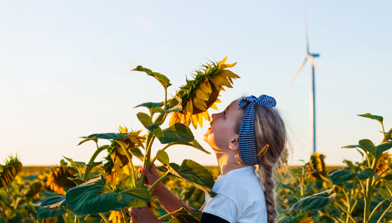 Mädchen riecht an einer Sonnenblume (Bild © Nestlé)